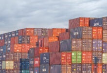 Image shows stacked shipping containers.