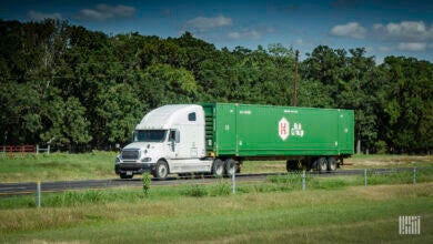 A white sleeper cab pulling a green Hub Group intermodal container