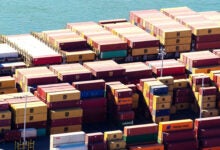 Image shows stacks of shipping containers and ocean.