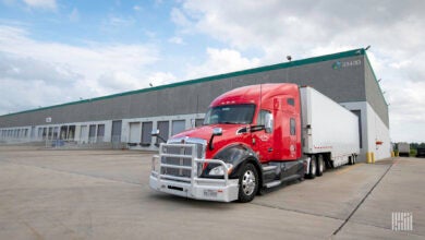 A red tractor with a white trailer backed up to a Prologis dock door