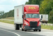 A red Saia daycab pulling a white Saia trailer