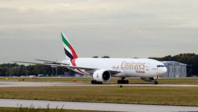 An Emirates SkyCargo jet with multi-colored tail lands on runway.