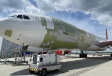 Closeup view of a large jet with patches on its fuselage where technicians have installed new sections to change the plane into a freighter.