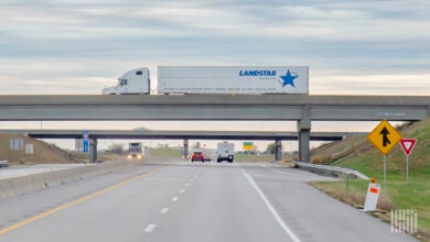 A white sleeper cab pulling a white Landstar trailer on an overpass