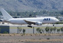 A white ATI cargo jet seen about to land at a desert airport.