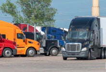 A black tractor with a white trailer pulling into a truckstop