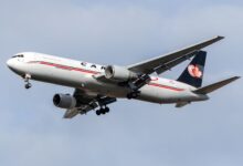 A Cargojet plane with dark blue tail seen from below as it approaches an airport.