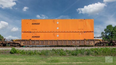 Orange Schneider intermodal containers double stacked on a well car