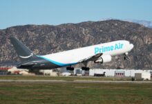 An Amazon Prime cargo jet takes off with desert mountains in the background.