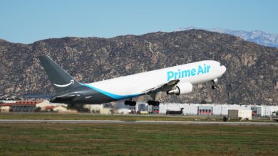 An Amazon Prime cargo jet takes off with desert mountains in the background.