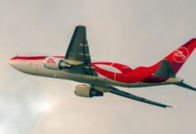 A red-and-white jetliner takes off into the clouds.