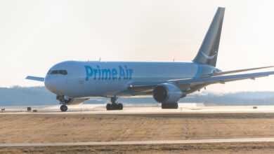 An Amazon Prime Air cargo jet with blue markings rolls forward on runway.