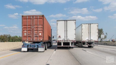 Rearview of one ocean container and two trailers being pulled on a highway