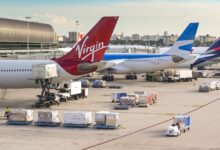 Virgin Atlantic and other passenger jets parked at their gates as vehicles move baggage and cargo carts to the loading bays.