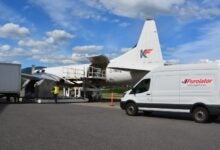 A Purolator delivery van on an airport tarmac next to a propeller cargo aircraft.