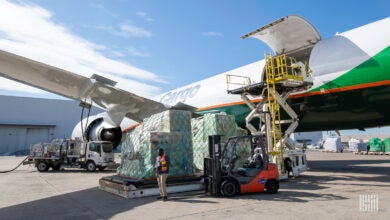 A cargo jet onboards a pallet of cargo and jet fuel from a tanker truck.