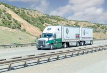 An Old Dominion tractor pulling two pup trailers on a highway