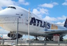 Front close up of an Atlas Air jumbo jet from behind a fence line.