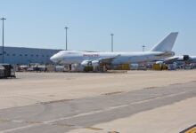 Two large cargo jets at an airport terminal on a sunny day.