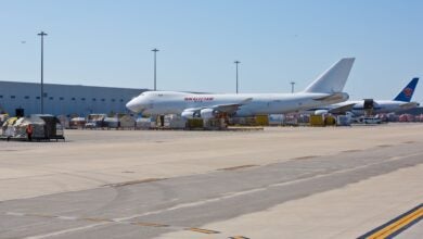 Two large cargo jets at an airport terminal on a sunny day.