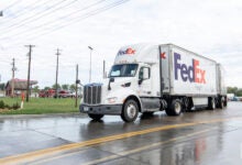 A FedEx tractor pulling two FedEx pup trailers