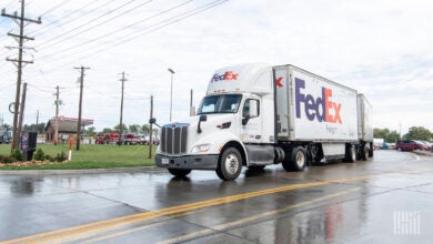 A FedEx tractor pulling two FedEx pup trailers