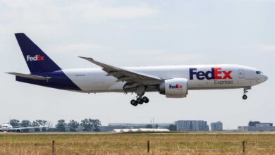 A purple-tail FedEx jet with wheels down for runway landing.