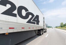 a white tractor pulling a white trailer with a 2024 banner on a highway