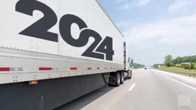 a white tractor pulling a white trailer with a 2024 banner on a highway