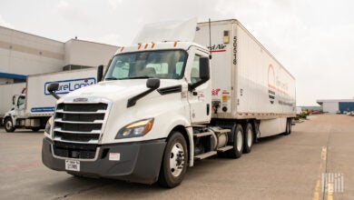 A Forward Air tractor trailer driving by an airport terminal