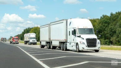 A white tractor pulling two white pup trailers on a highway