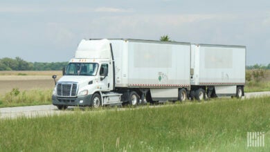 A white daycab pulling two white pup trailers on a highway