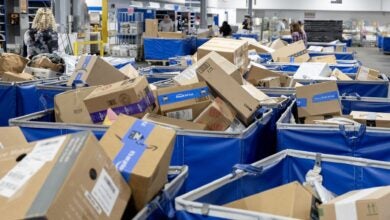 Piles of packages in bins at a U.S. Postal Service facility.