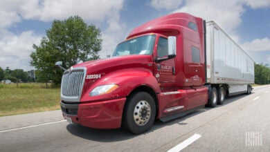 A maroon Knight sleeper cab pulling a white Knight dryvan trailer on a highway