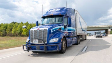 A blue Marten tractor pulling a white Marten trailer on a highway