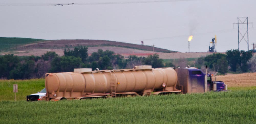  An empty oil truck passes in front of oil wells flaring gas in McKenzie County west of Watford City, North Dakota. Few pipelines exist in North Dakota, so most oil is trucked out daily from each well.  (Photo:  Tim Evanson , Wikimedia Commons)  