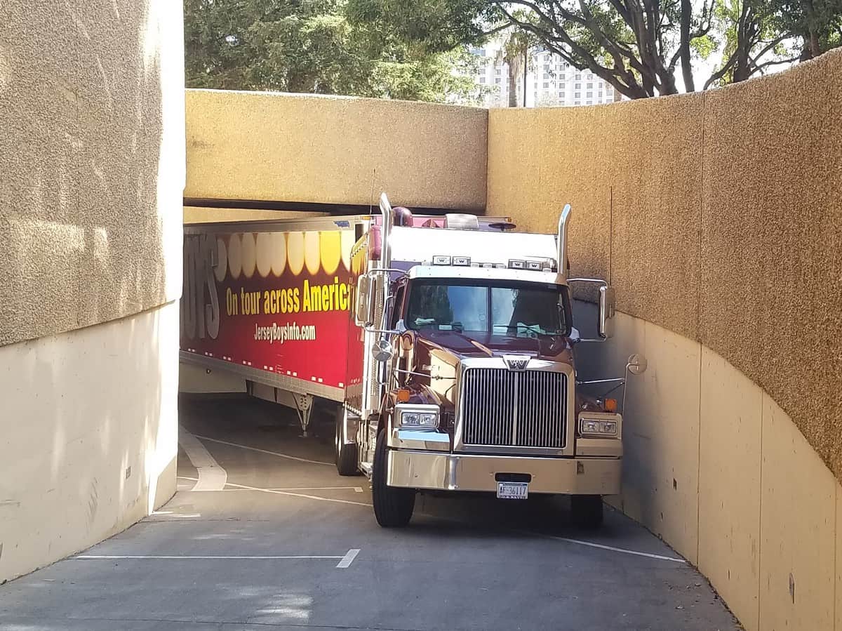 A photograph of a truck and trailer driving up a narrow passageway.