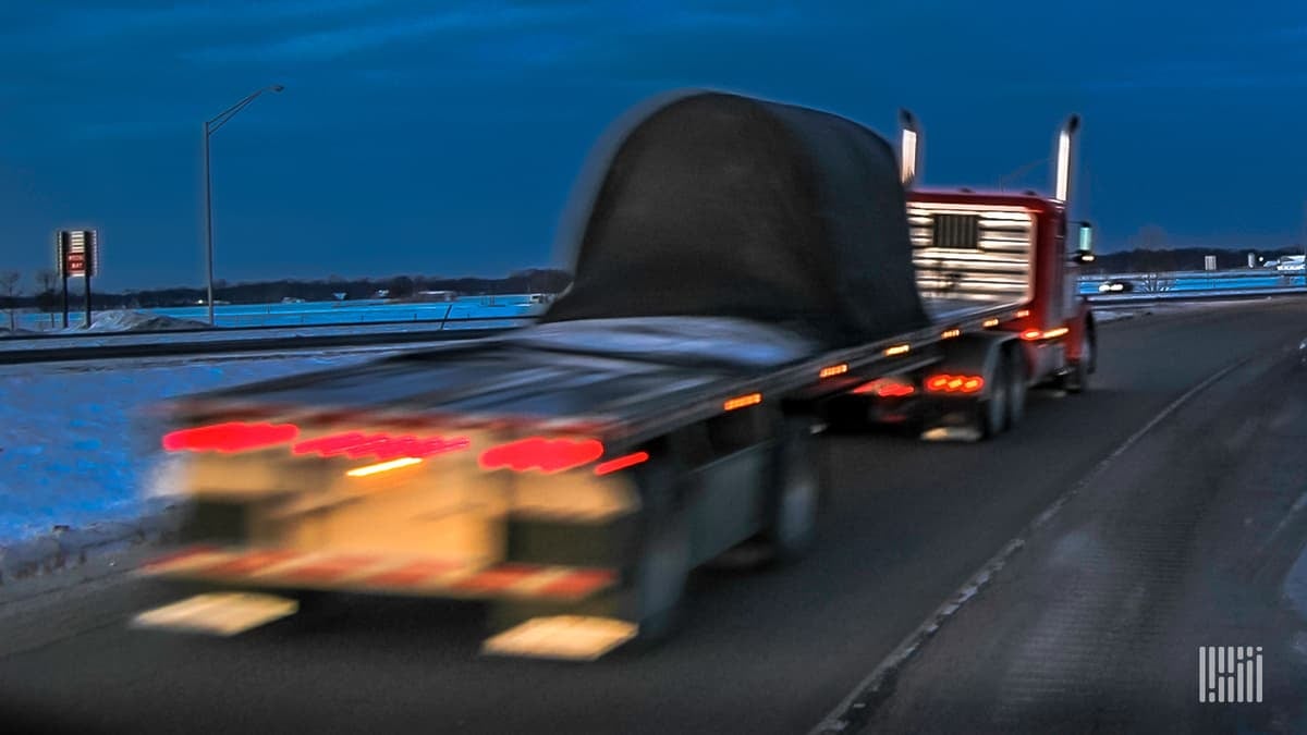 Flatbed truck on highway at night.