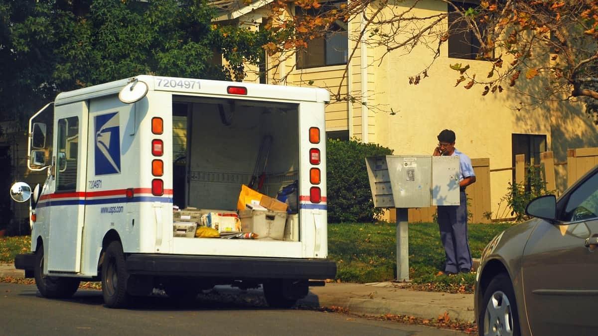 USPS truck and mailman delivering mail.