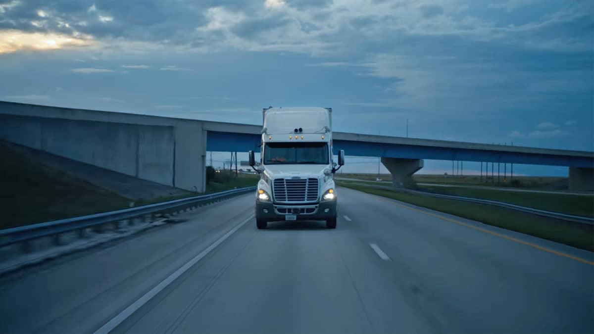 A Starsky autonomous truck drives down the highway at dusk.