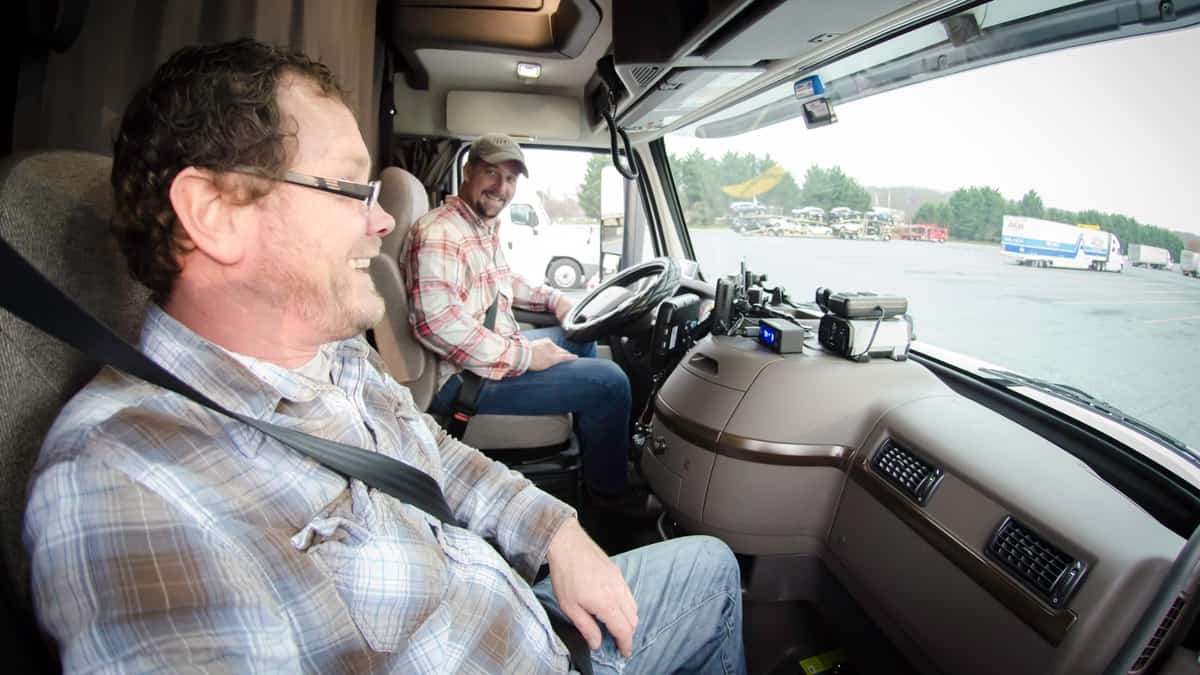 Two truck drivers smiling at each other.