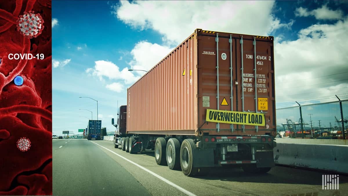 Truck moving down highway with "Overweight" banner on back end.