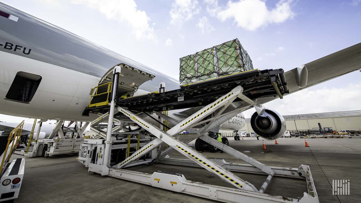 Machine lifts cargo pallets up to door of plane for loading.