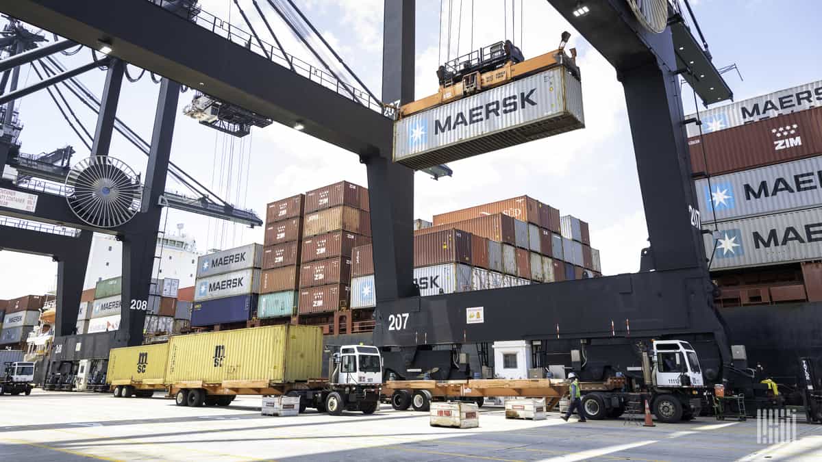 An intermodal container is unloaded from a ship for transport by truck.