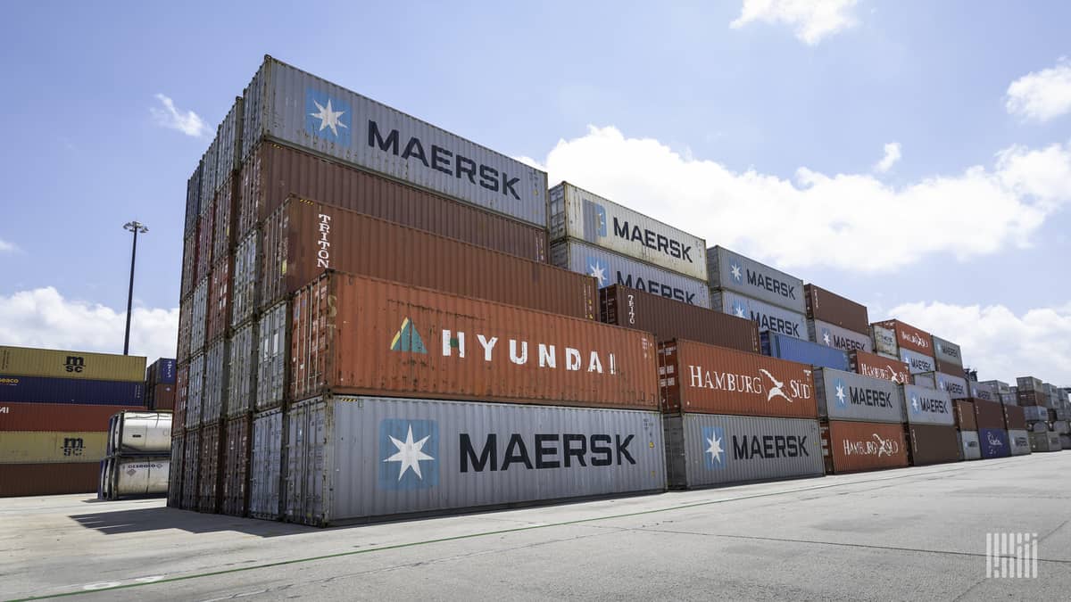 Containers rise five-high at a dockyard holding area.