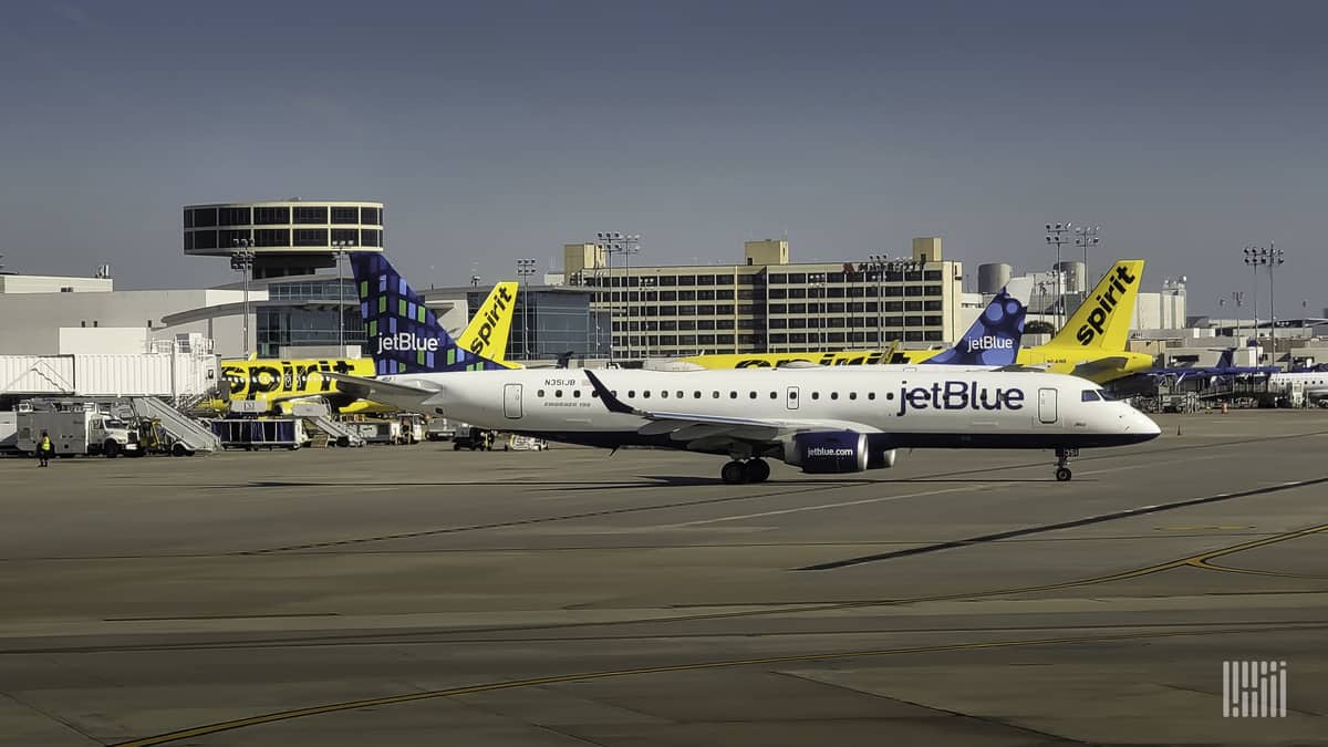 A small white and blue jet on the tarmac with a yellow jet in the background.