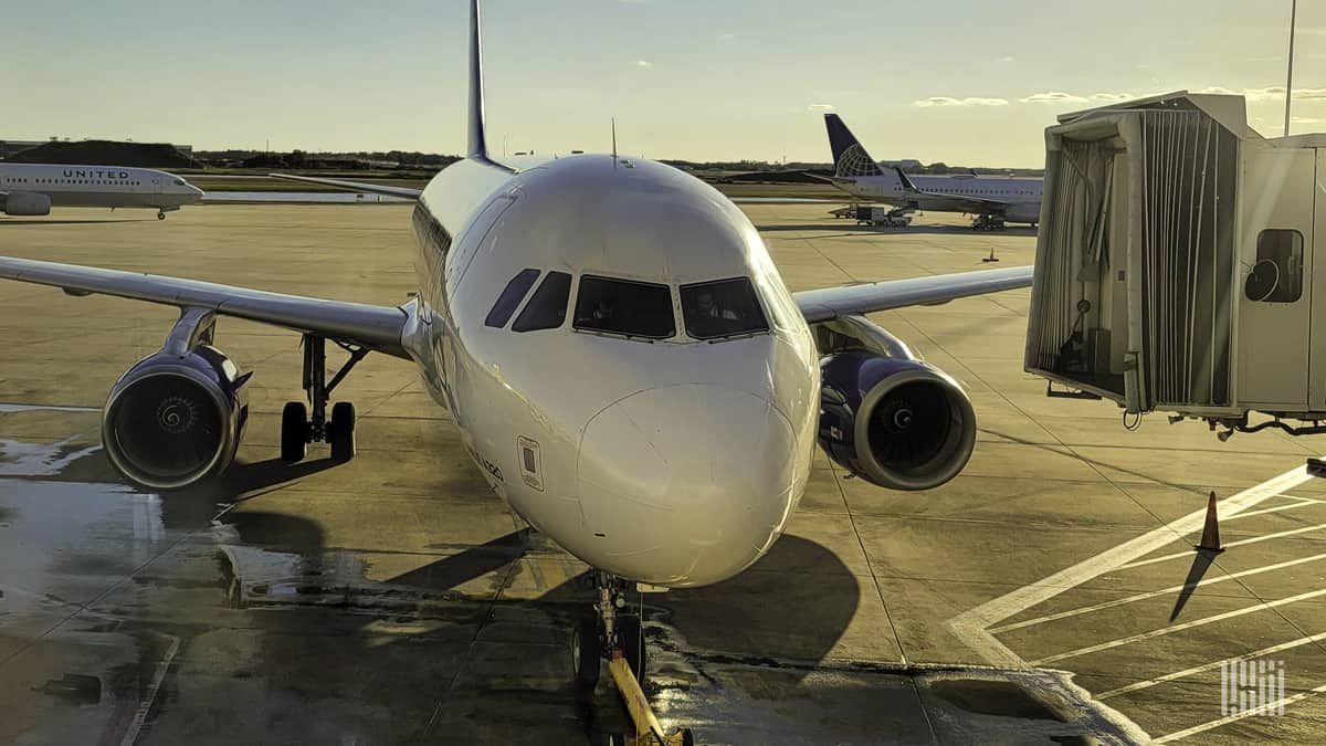 A small passenger jet parked at the gate on a sunny morning, looking straight out at cockpit.