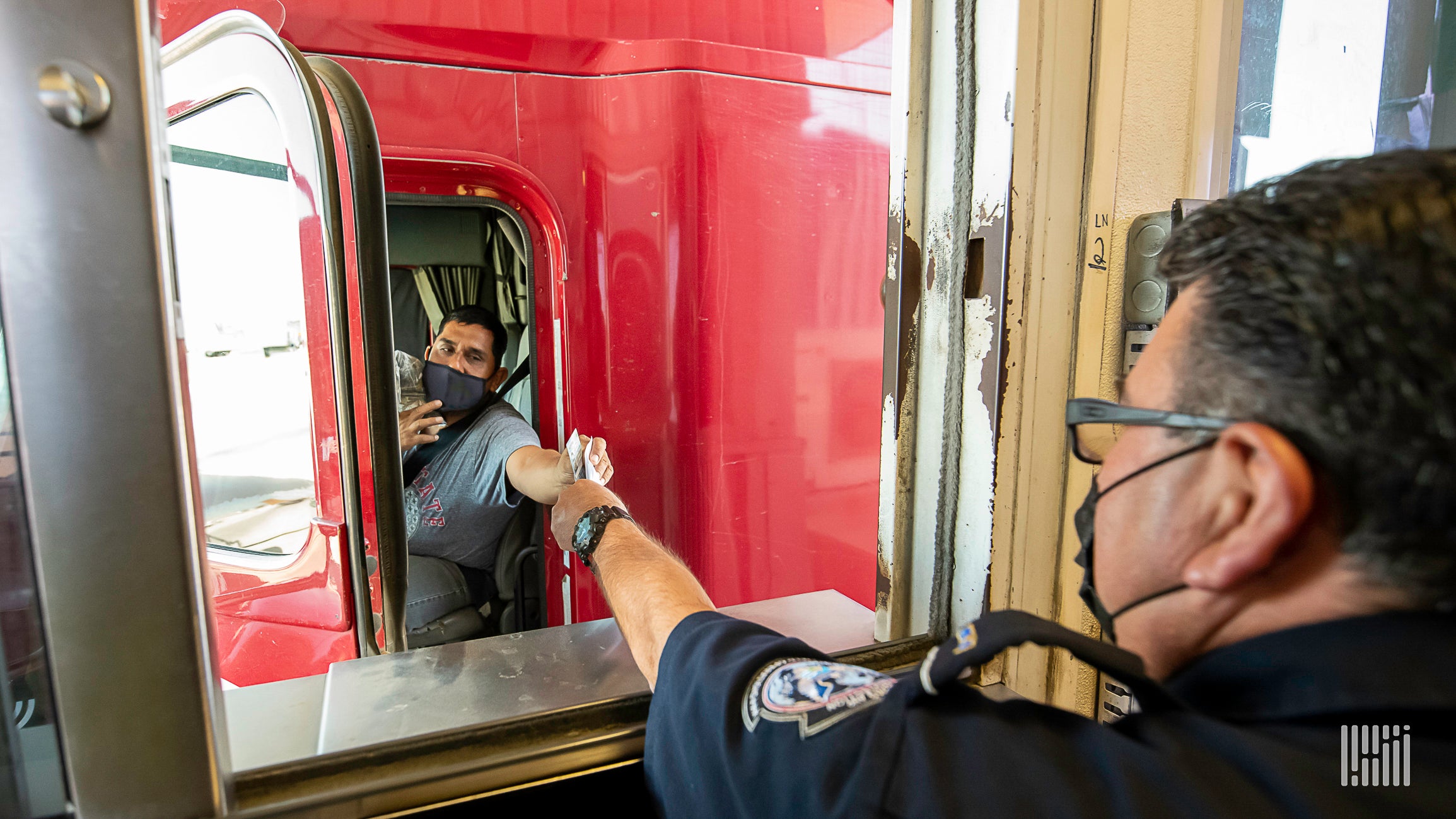 a truck driver handing documents to a US border officer.