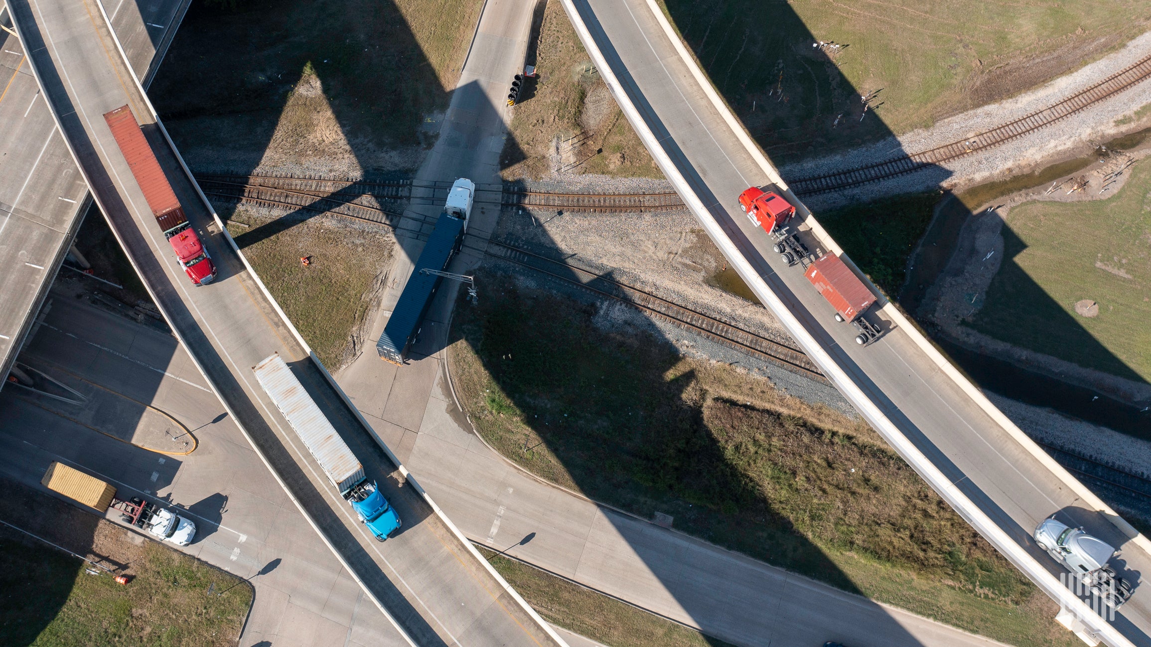 An aerial view of semi-trucks passing on major roads are moving goods.