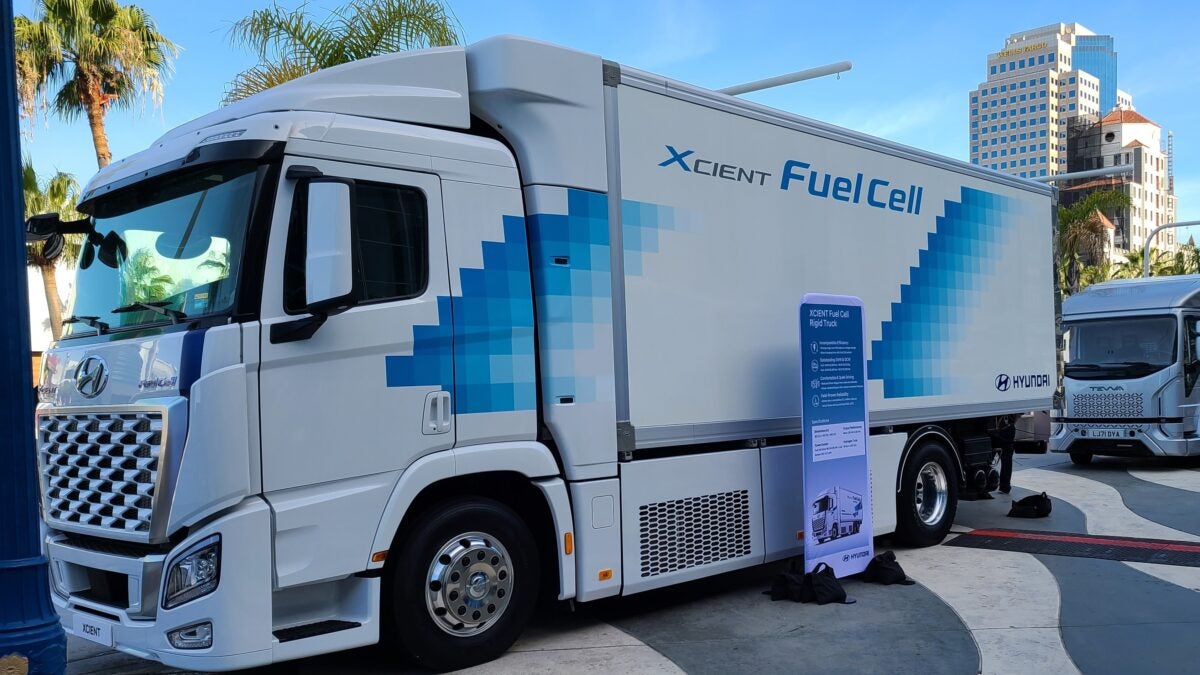 A  white Hyundai Xcient fuel cell truck with graphics outside the Long Beach Convention Center